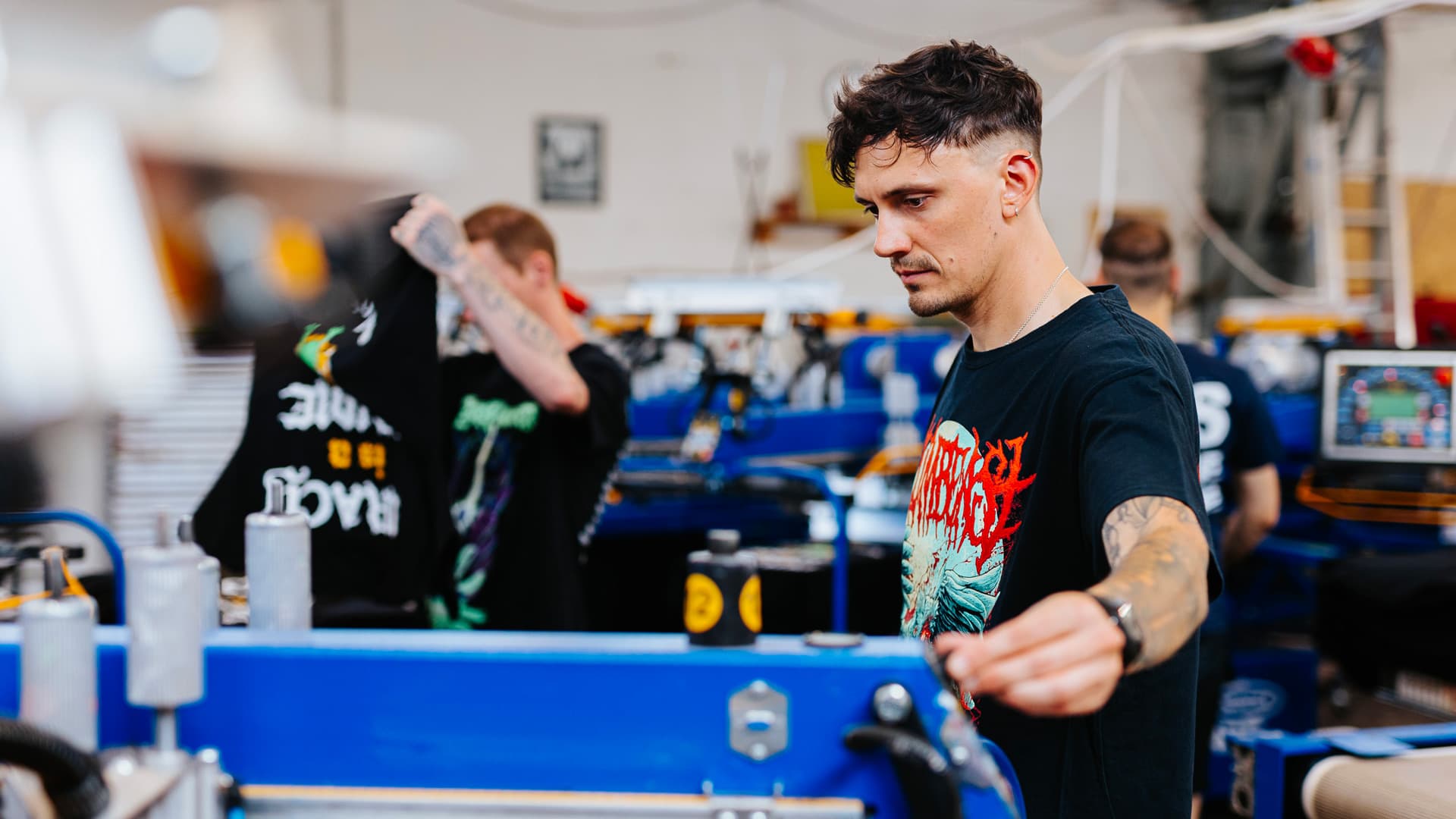 Screen printing operators creating custom metal band merchandise at Real Pimp Budapest workshop