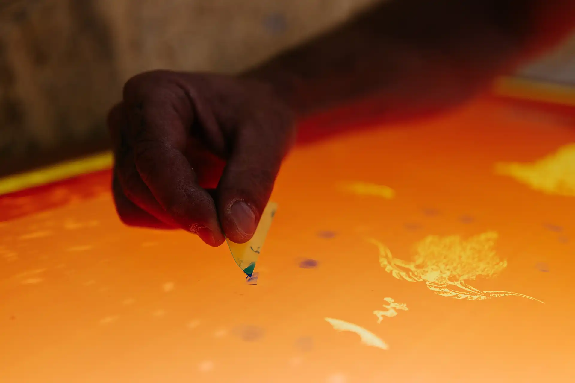 Peeling protective sheet from vibrant orange plastisol screen printing ink during production