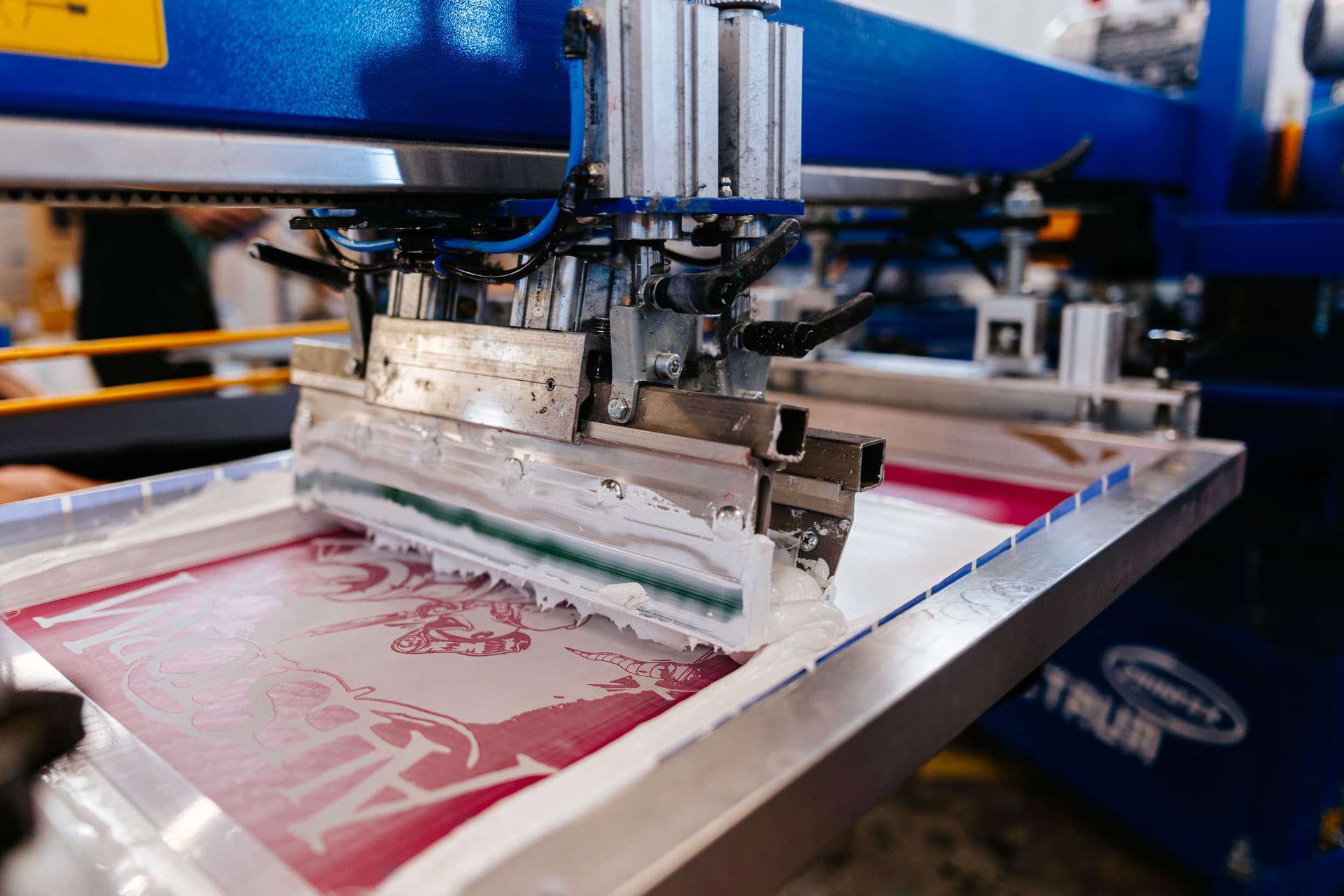Carousel screen printing machine applying pink ink design on custom band t-shirt